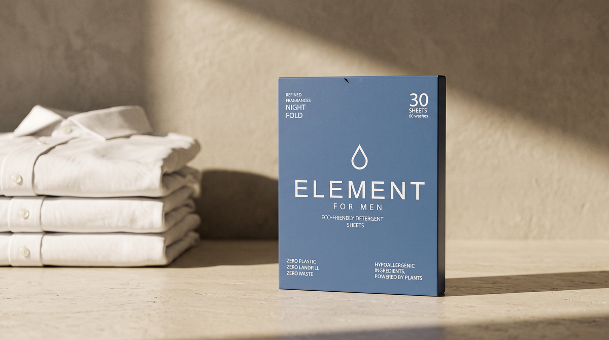 An Element for Men Night Fold detergent sheet carton standing on a limestone worktop beside a stack of folded white cotton shirts in afternoon light