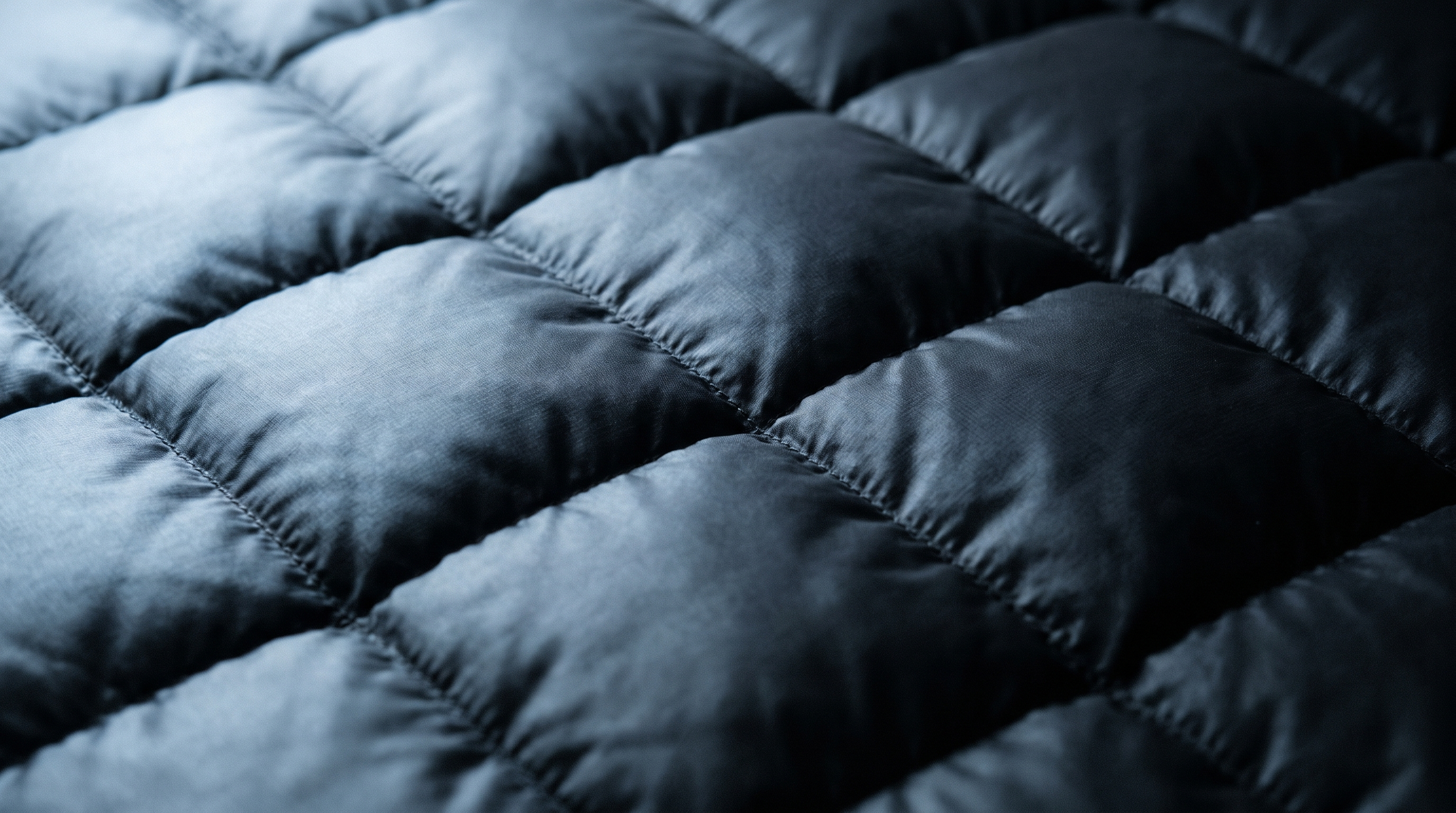 Close detail of the lofted quilted baffles of a matte black down jacket